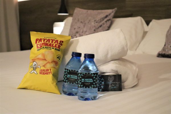 Detalle de Bienvenida en el Hotel Yomo Eureka. 2 botellitas de agua y una bolsa de patatas de la marca Espinaler